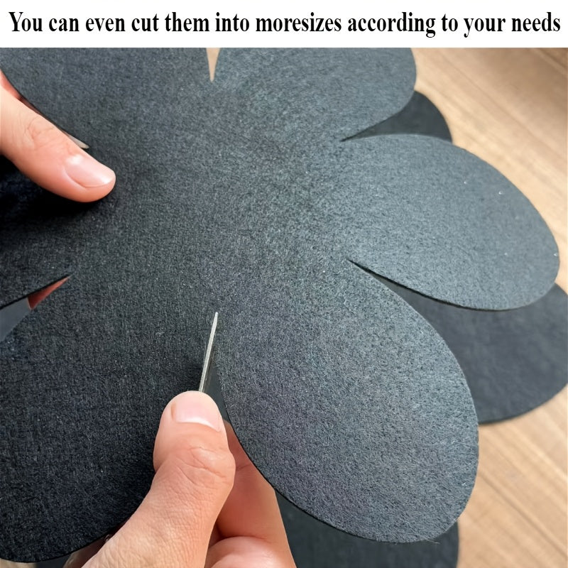 Set of 4 black petal-shaped pan pads made of non-woven, non-stick material. These pads are non-slip, anti-scalding, and provide heat insulation. They are easy to clean and made of multi-ply felt cloth.