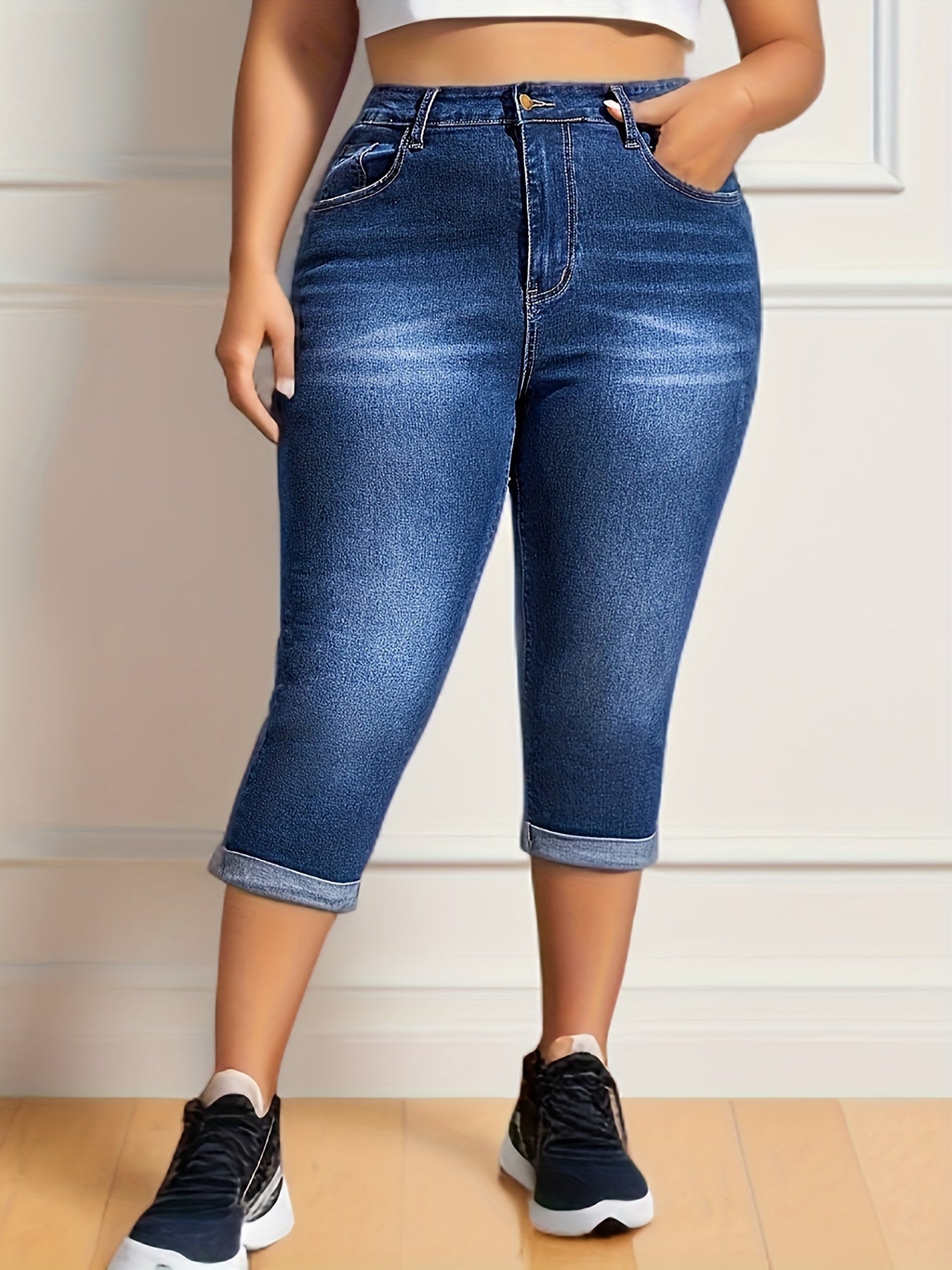 Plus size women's high stretch capri denim pants in washed blue with whiskering and roll-up hem.