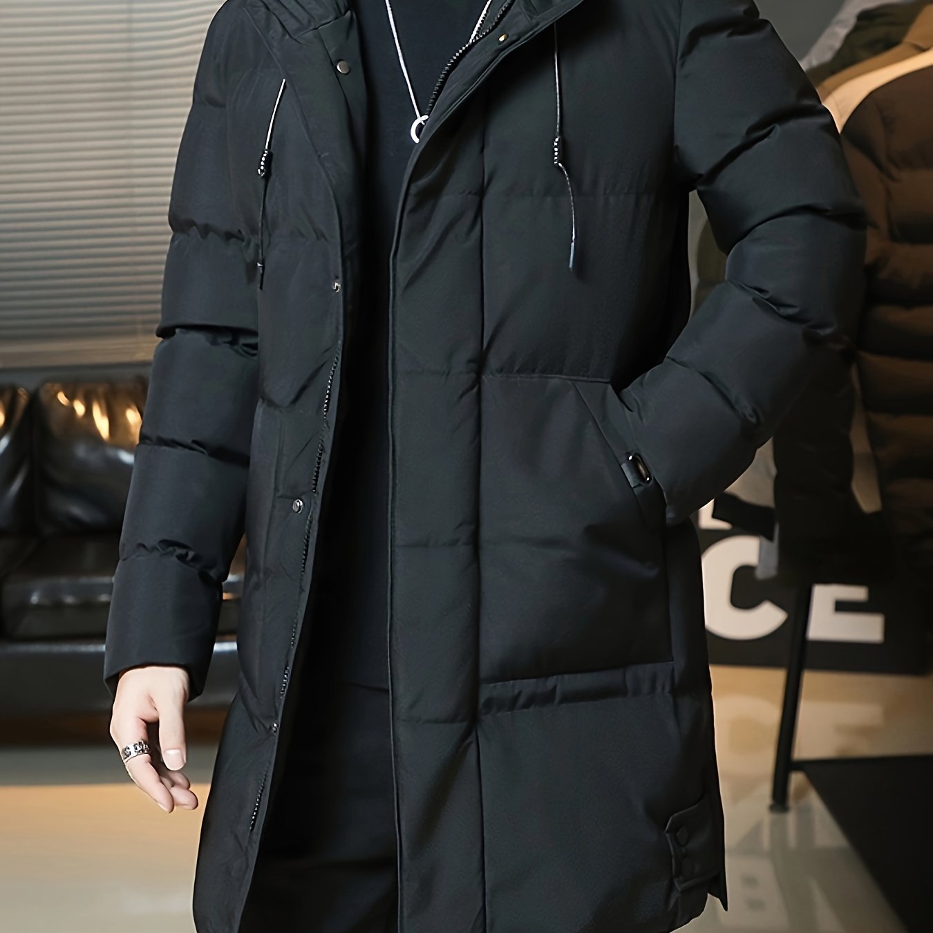 Men's long hooded jacket made of warm, thick polyester with large pockets. Zip-up winter coat in black for casual outfits. Spacious pocket design and durable winter wear.