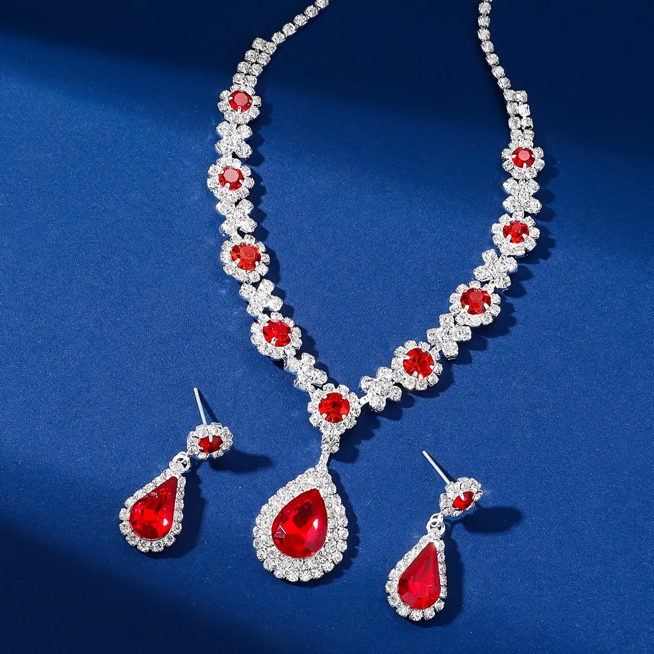 Stylish and opulent silver plated necklace and earrings set adorned with red rhinestone flower detailing and teardrop pendants. This elegant copper fashion jewelry set is designed for women, ideal for parties, banquets, and Valentine's Day. A versatile